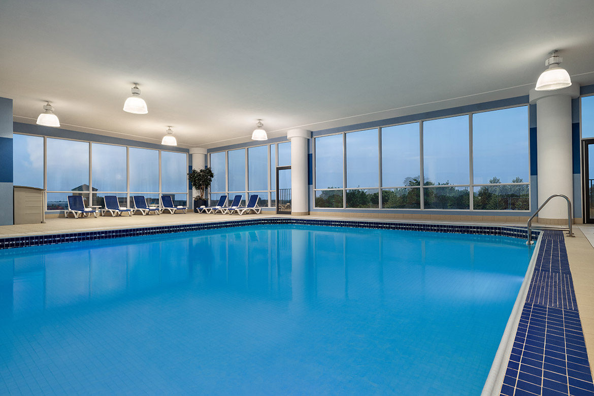 A serene indoor pool surrounded by comfortable seating and natural light streaming in from expansive windows.