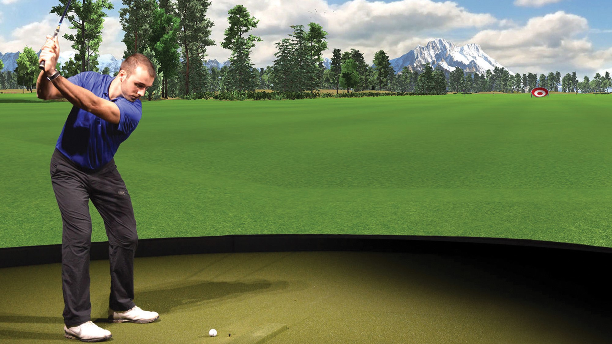 A man is engaged in a golf simulation, swinging a club while focused on the virtual course displayed on the screen.