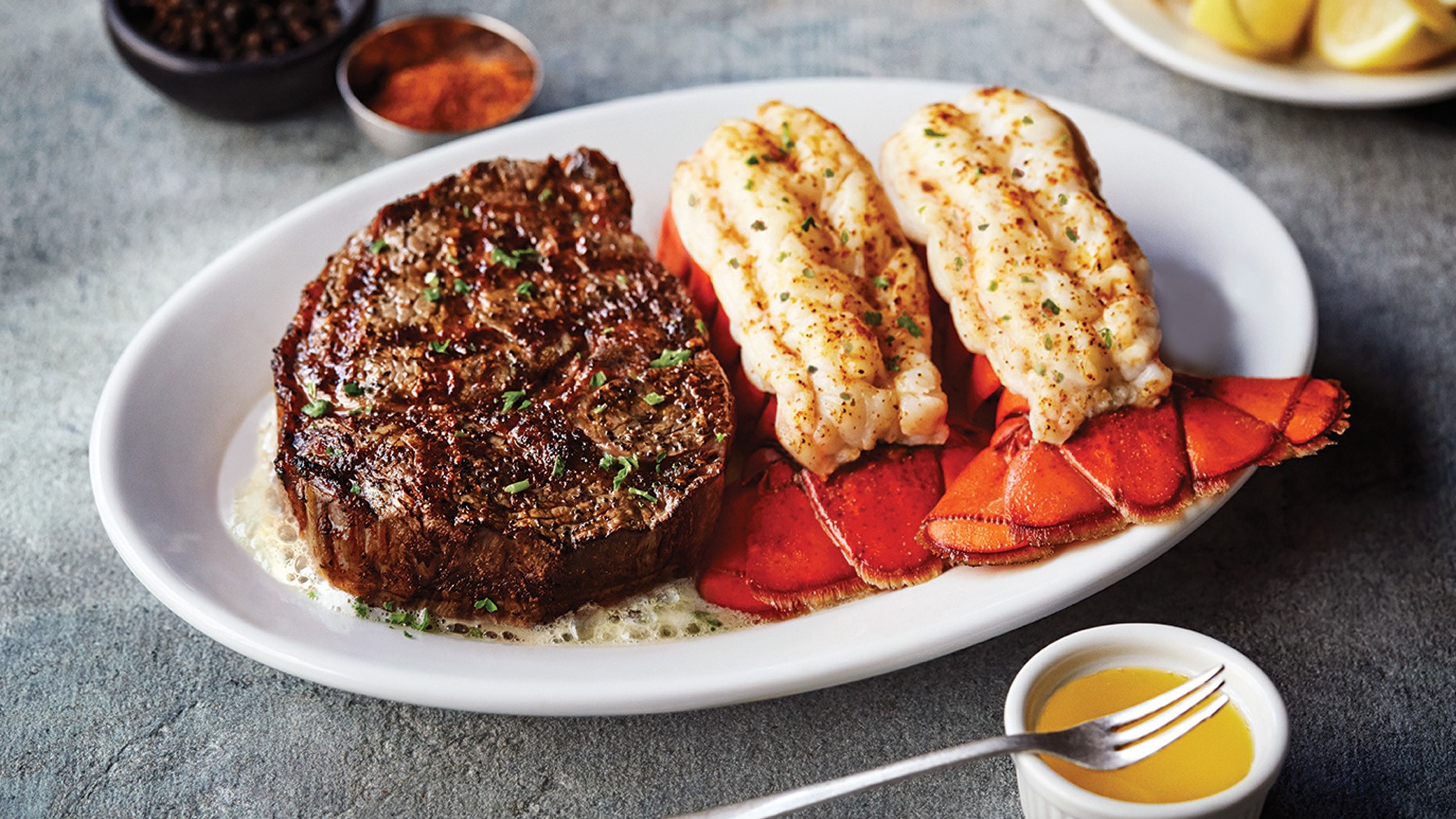 A beautifully arranged plate featuring a succulent steak alongside a perfectly cooked lobster, garnished elegantly.