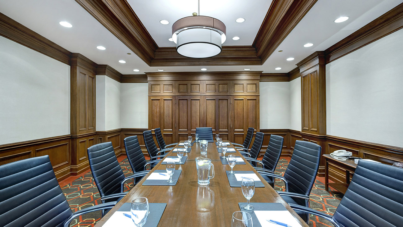 An elegant conference room with a long table and numerous chairs, designed for professional meetings and discussions.