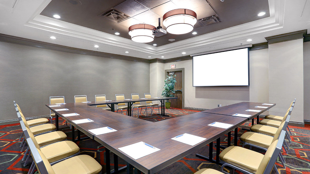 A well-appointed conference room showcasing a large central table with multiple chairs arranged around it for collaborative sessions.