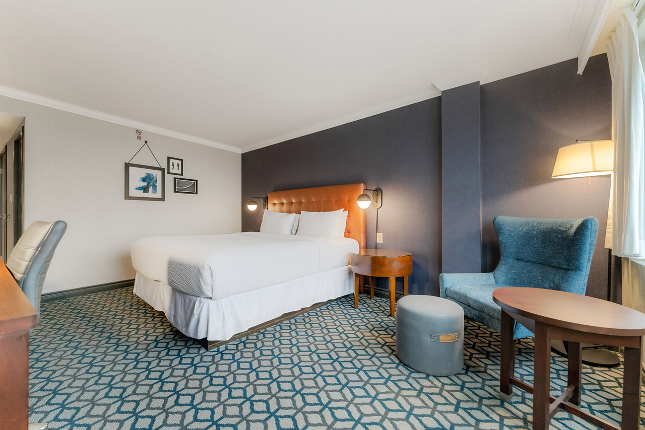 A hotel room featuring blue walls and a neatly made bed, creating a serene and inviting atmosphere for guests.