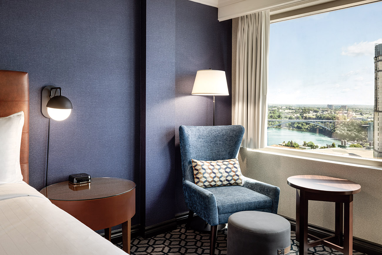 An elegant hotel room with a picturesque view of Niagara Falls through its expansive window.