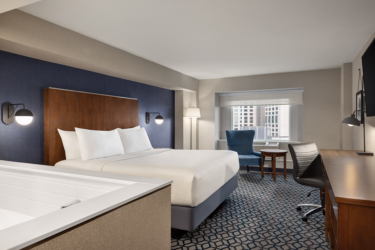 A luxurious hotel room featuring a spacious king bed and an inviting jacuzzi tub for relaxation and comfort.