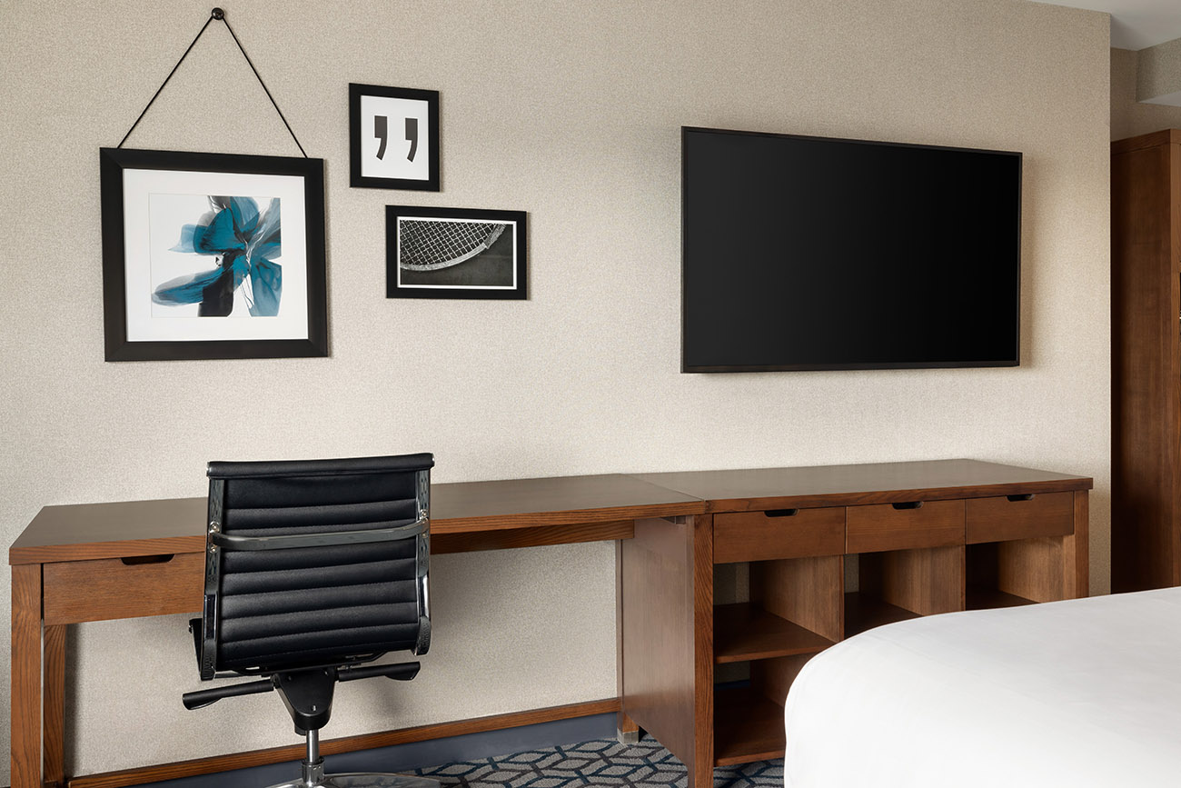 A cozy hotel room equipped with a desk, chair, and television, providing a functional space for guests.