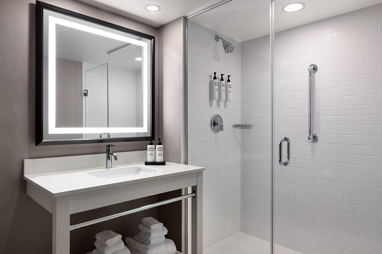 A clean bathroom featuring a modern shower and a sleek sink, showcasing a minimalist design and bright lighting.