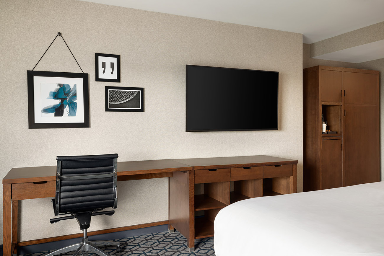 A cozy hotel room equipped with a desk, chair, and television, providing a functional space for guests.