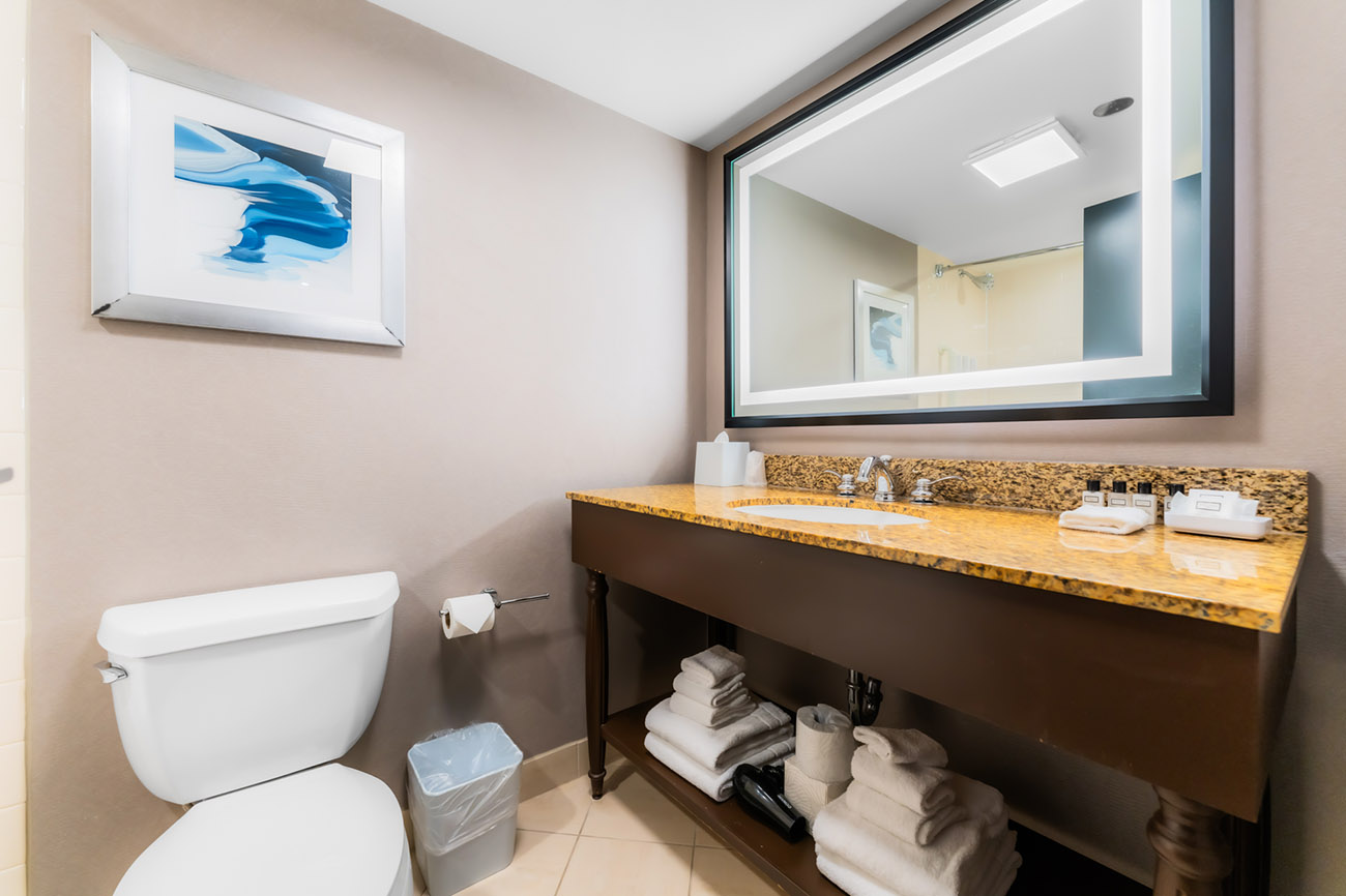 A clean bathroom featuring a toilet, sink, and mirror, showcasing a modern and functional design.