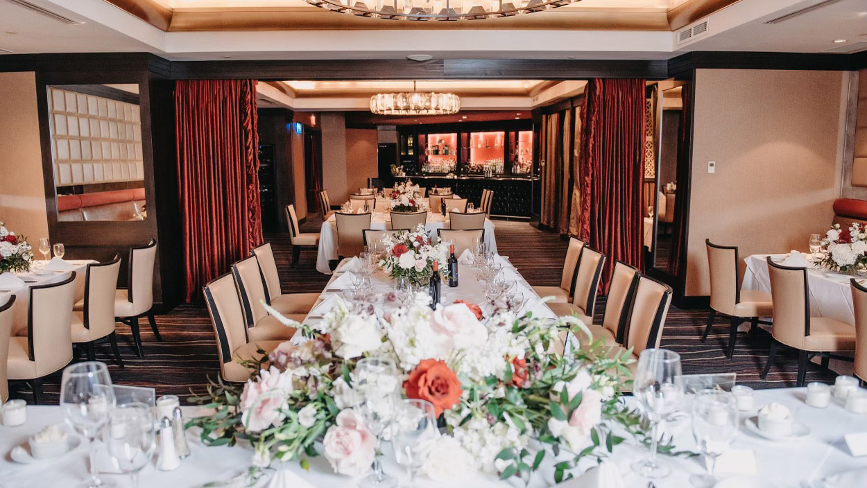 A sophisticated dining room showcasing a beautiful chandelier and several tables, perfect for upscale dining events.